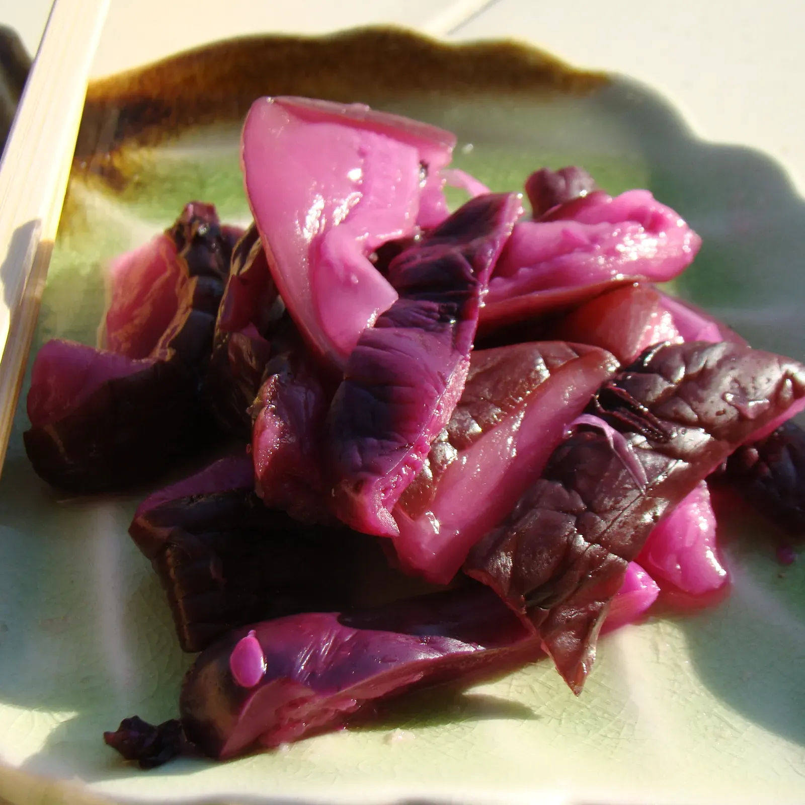 Purple shibazuke on a green plate with chopsticks