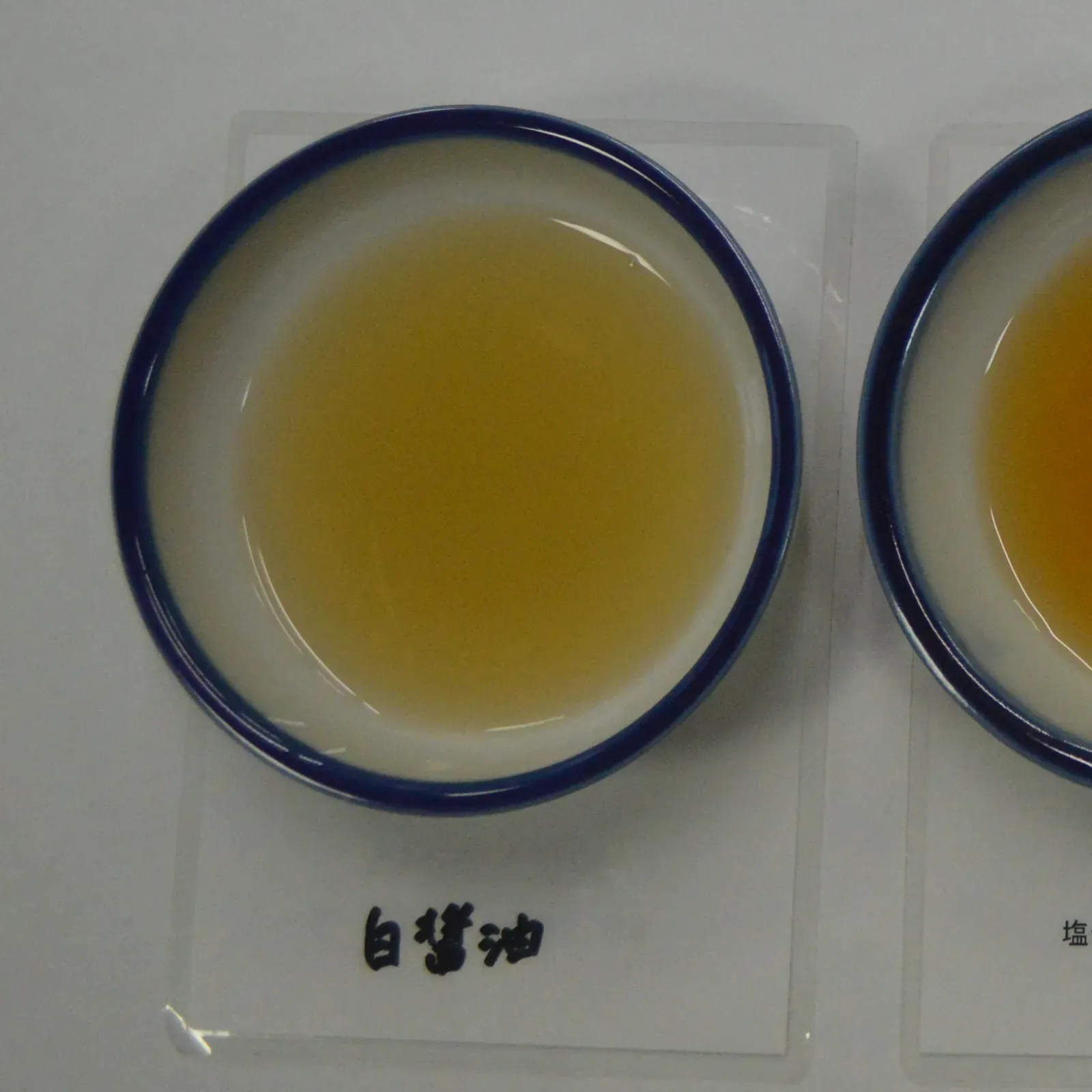 Tasting cup of pale amber shiro shoyu, labeled 白醤油